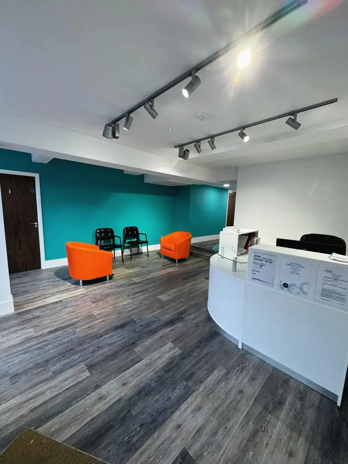Reception area with white desk and orange chairs in a bright office